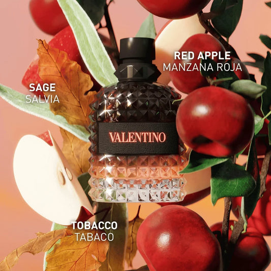 A textured glass perfume bottle labeled VALENTINO with a black cap, surrounded by red apples, green leaves, and autumn leaves on a peach-toned background. White text overlays read SAGE SALVIA, RED APPLE MANZANA ROJA, and TOBACCO TABACO.