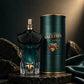 Jean Paul Gaultier Le Beau Le Parfum perfume bottle with a dark teal and black body, gold spray top, and gold leaf detail, displayed next to its dark green cylindrical box with gold lettering on a marble pedestal.
