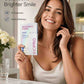 Woman holding INOPRO whitening strips with a bright smile in a bathroom setting