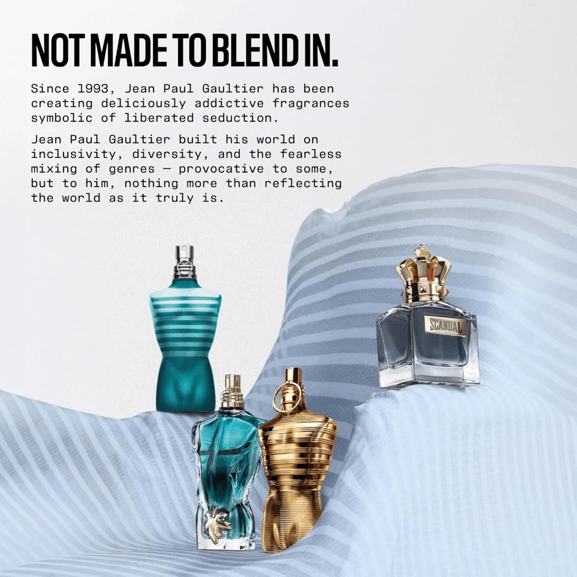 Three Jean Paul Gaultier perfume bottles displayed on a draped light blue fabric surface with promotional text on a white background. The bottles include a teal ribbed bottle, a translucent blue bottle with a gold atomizer, and a metallic gold ribbed bottle with a gold crown cap.