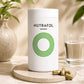 A white cylindrical bottle labeled 'NUTRAFOL WOMEN' with a green concentric circle logo, standing on a round stone coaster. Gold capsules are scattered beside it, with a glass of water and soft-focus plants in the background.