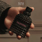 A hand holding a textured black Valentino perfume bottle with a pink brand label. The image includes text overlay indicating the size as 3.