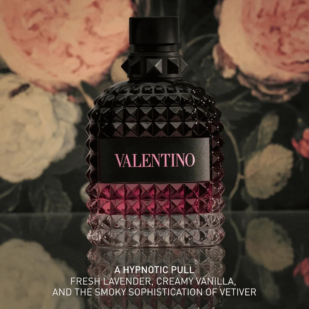 A Valentino perfume bottle with a textured faceted design, featuring a black top and a black label with pink 'VALENTINO' lettering. The bottle is set against a dark floral background with pink and cream roses, with product description text at the bottom.